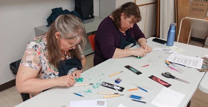 Deux participantes gravant leur plaque de linoléum...
