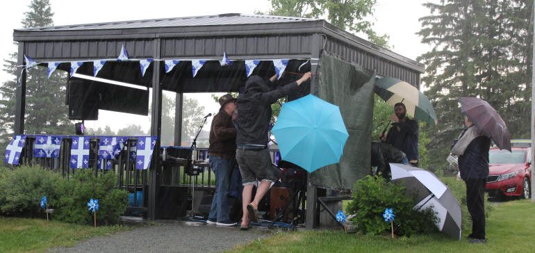 Des spectateurs entourent les chanteurs avec leurs parapluies