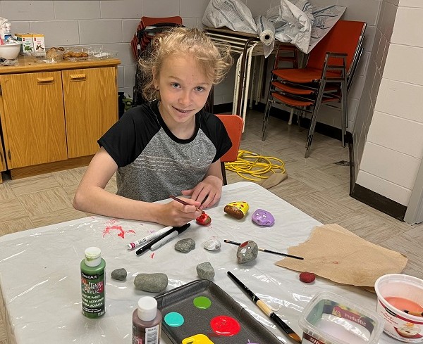 Jeune fille colorant des cailloux à l'aide d'un pinceau...