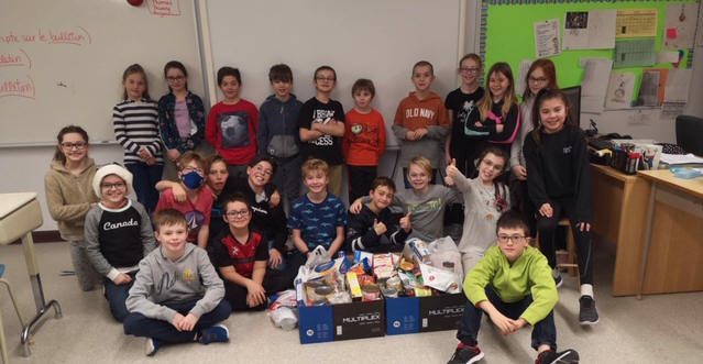 Groupe d'enfants devant deux boites de denrées.