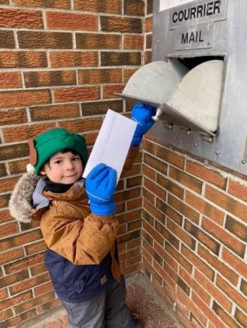 Un enfant dépose une lettre dans la boite de courrier.