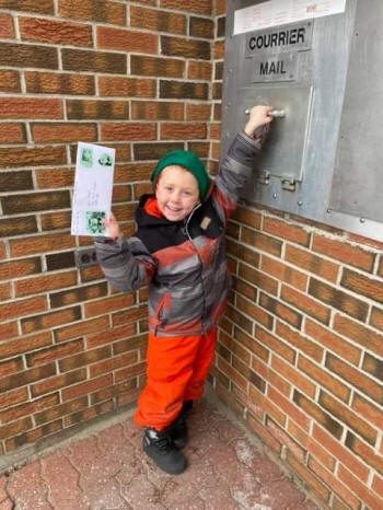 Un enfant souriant poste une carte au père Noël