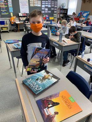 Un enfant choisit un livre parmi ceux sur la table