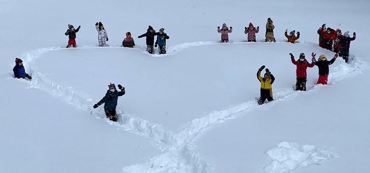 Groupe d'enfants traçant un immense coeur dans la neige