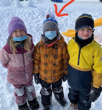 Enfants en habits d'hiver, l'un d'eux ayant un chiffre sur sa tuque...