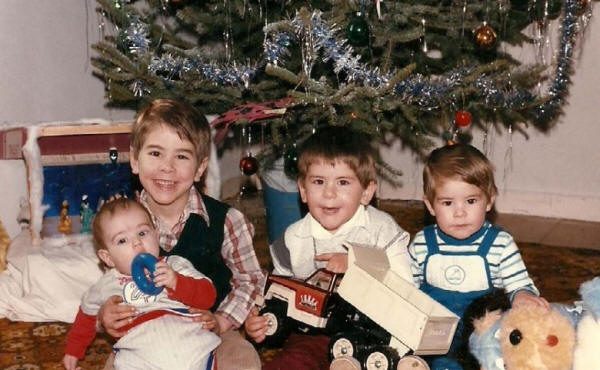 Quatre jeunes enfants devant un sapin de Noël